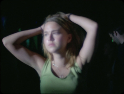 a woman in a green tank top holding her hair