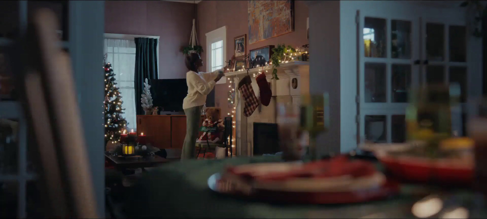 a woman standing in a living room next to a christmas tree