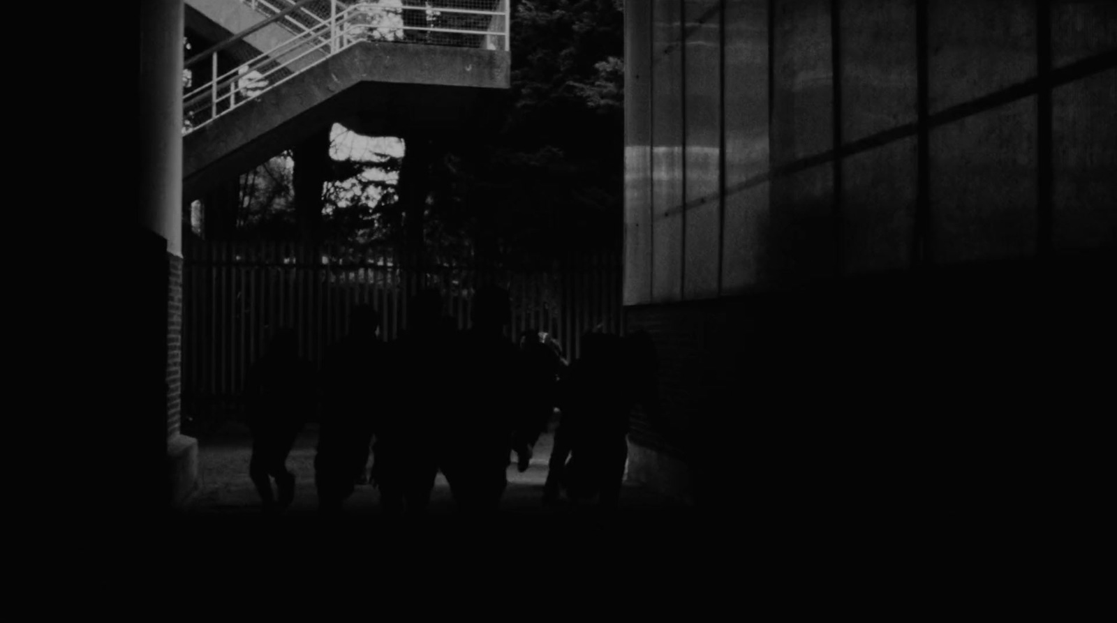 a group of people walking down a sidewalk next to a tall building