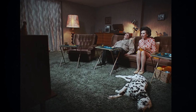 a man and a woman sitting on a couch with a dalmatian dog