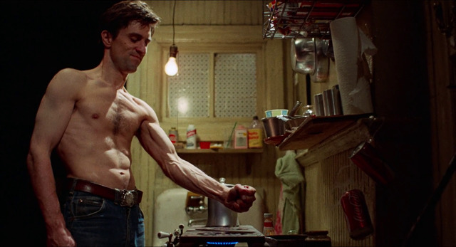 a shirtless man standing in a kitchen next to a stove