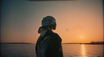 a person standing on a boat watching the sun set