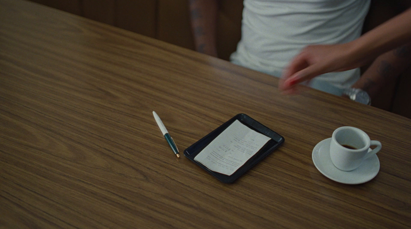 a person is writing on a piece of paper next to a cup of coffee