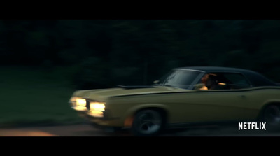 a yellow car driving down a road next to a forest