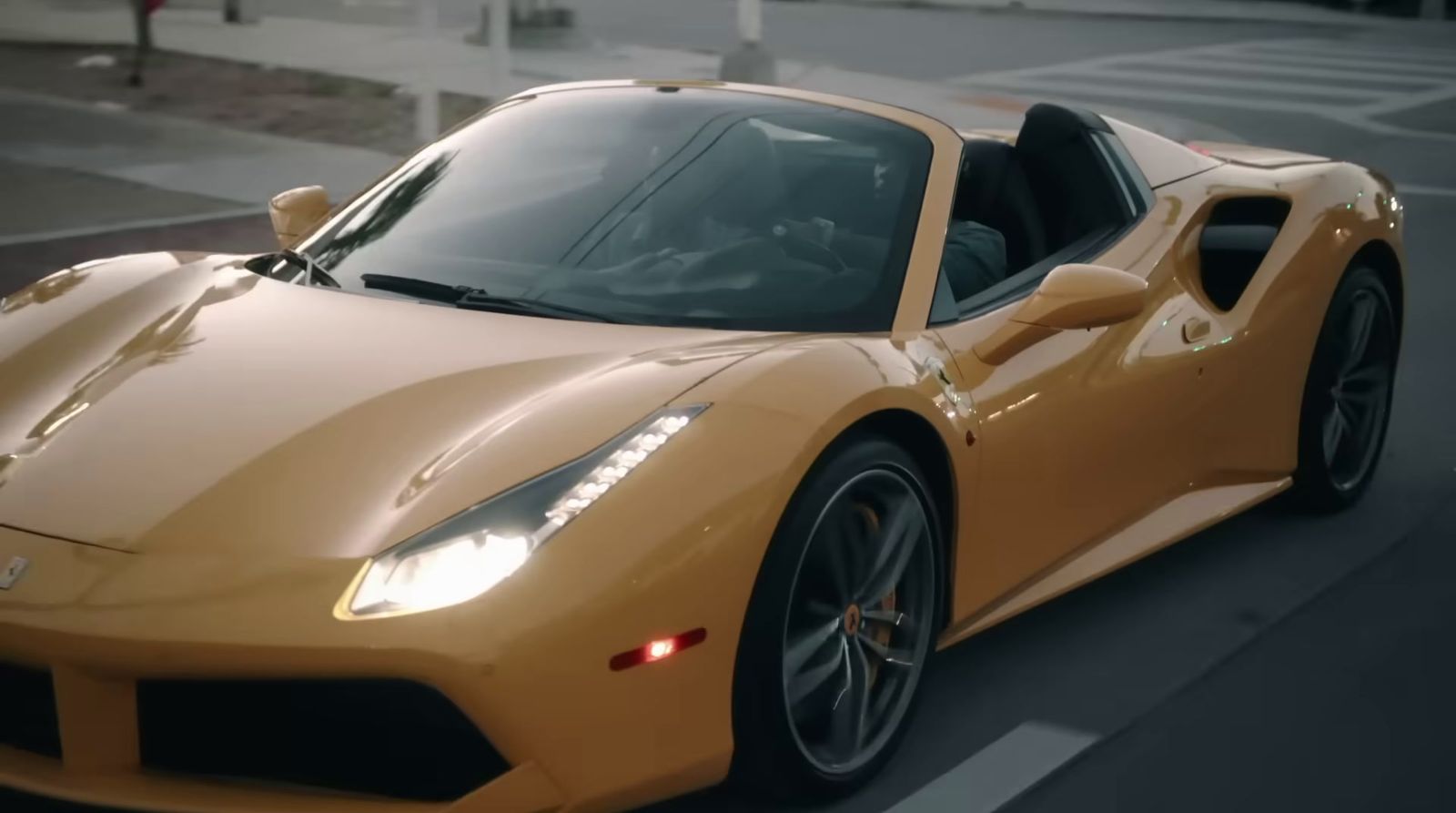 a yellow sports car driving down a street