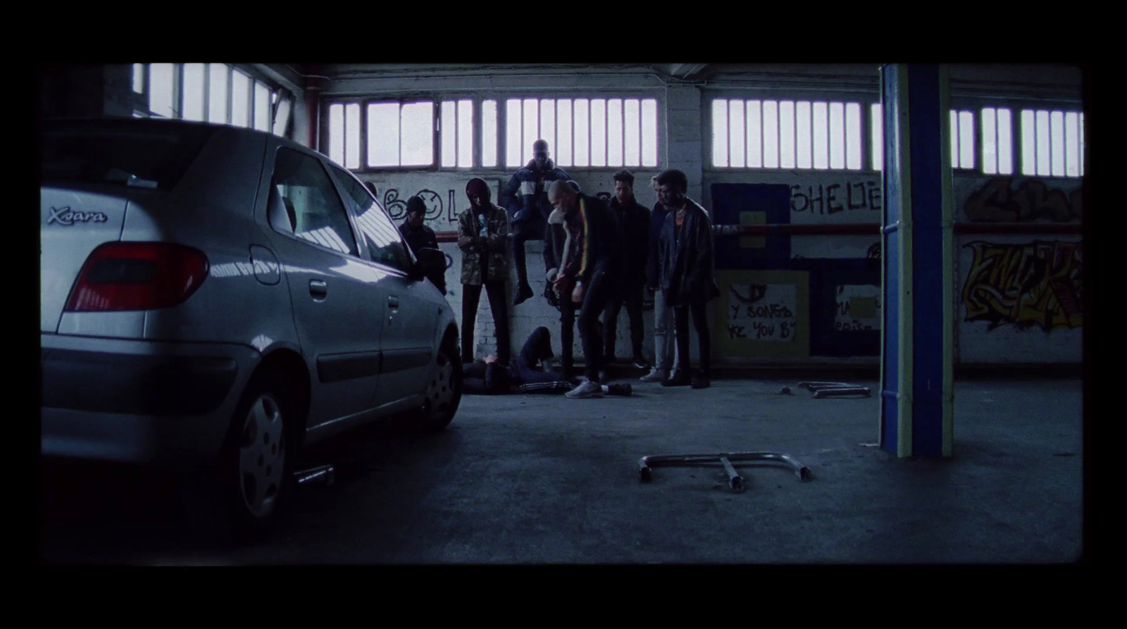 a group of young men standing next to a parked car