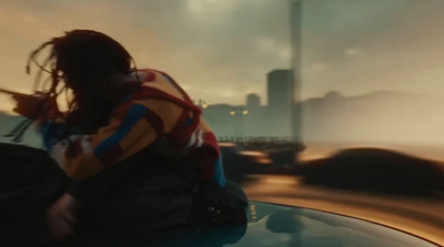 a man sitting on top of a car next to a tall building