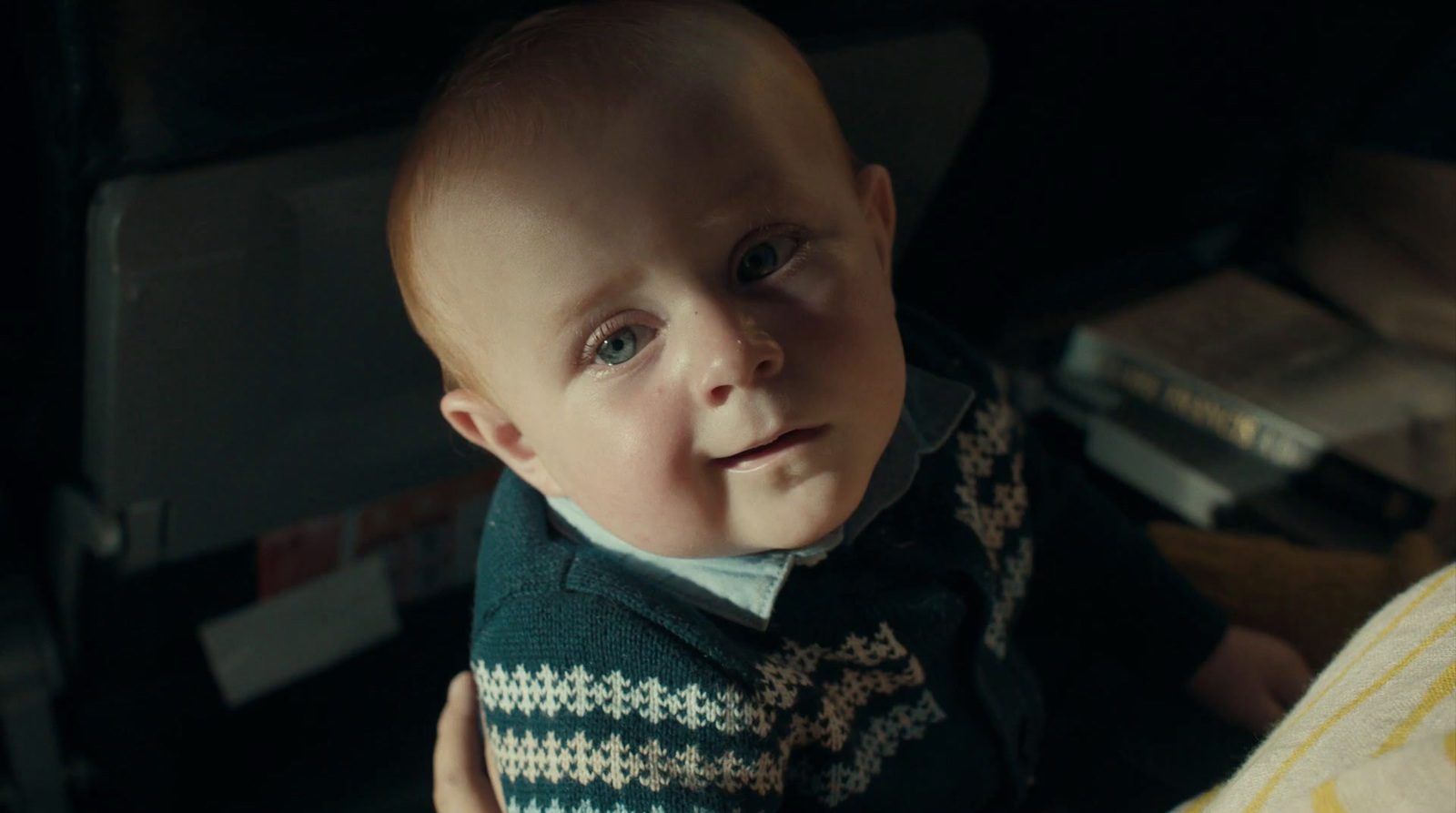 a baby with a sweater on staring at the camera