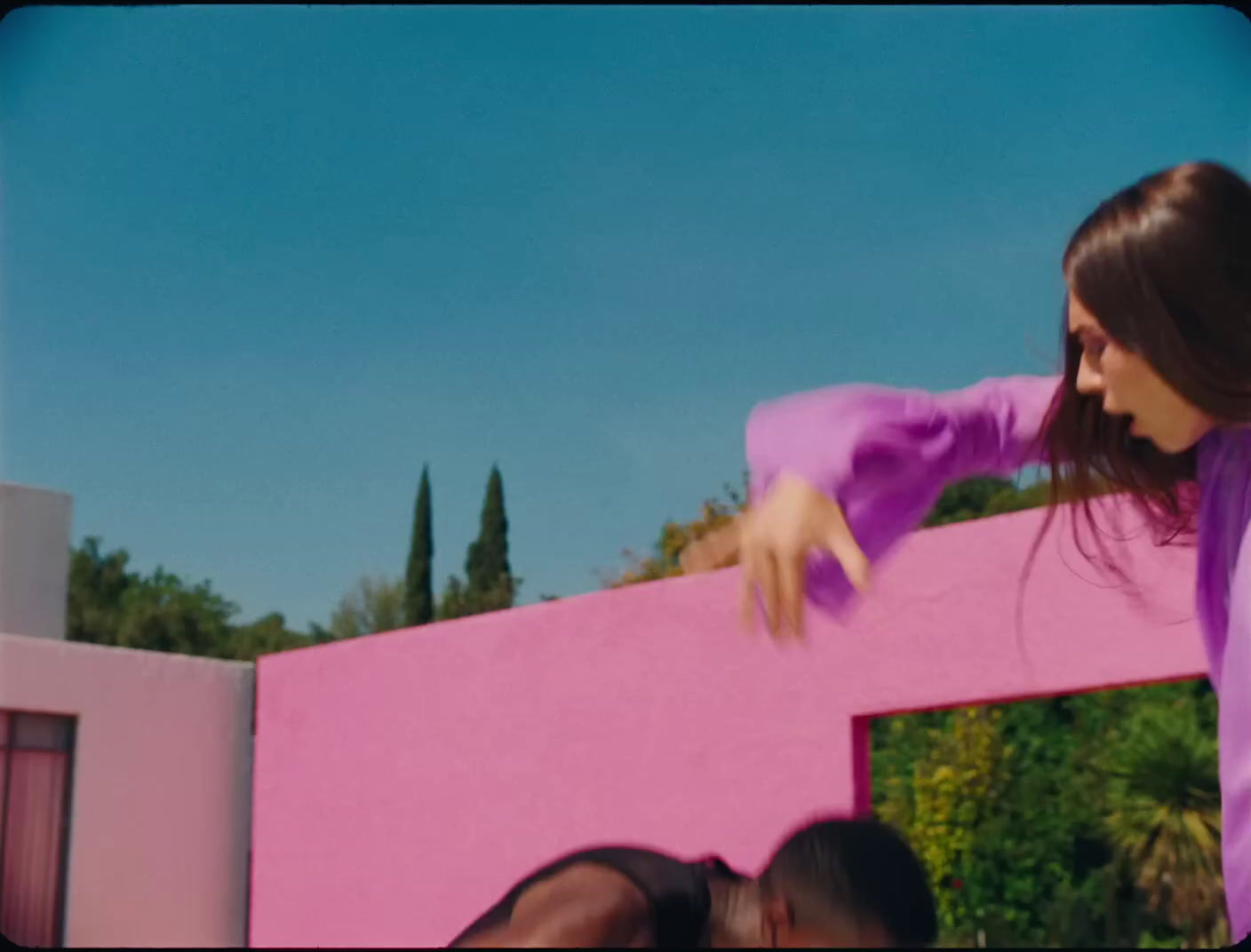 a woman in a purple shirt is doing a trick on a skateboard