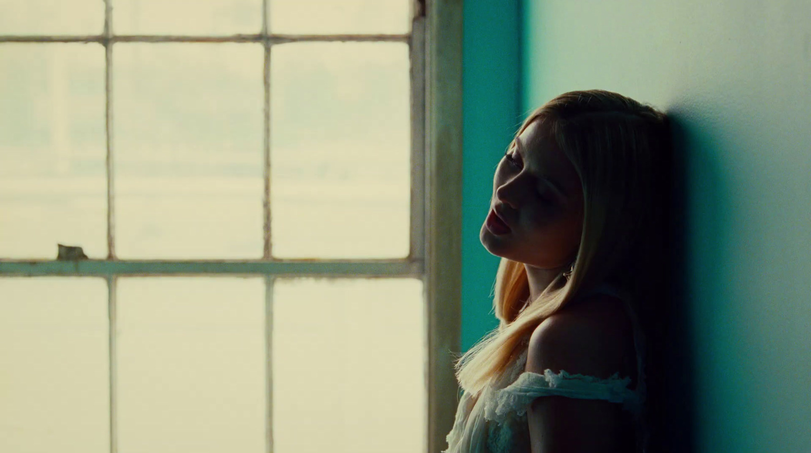 a woman leaning against a wall next to a window