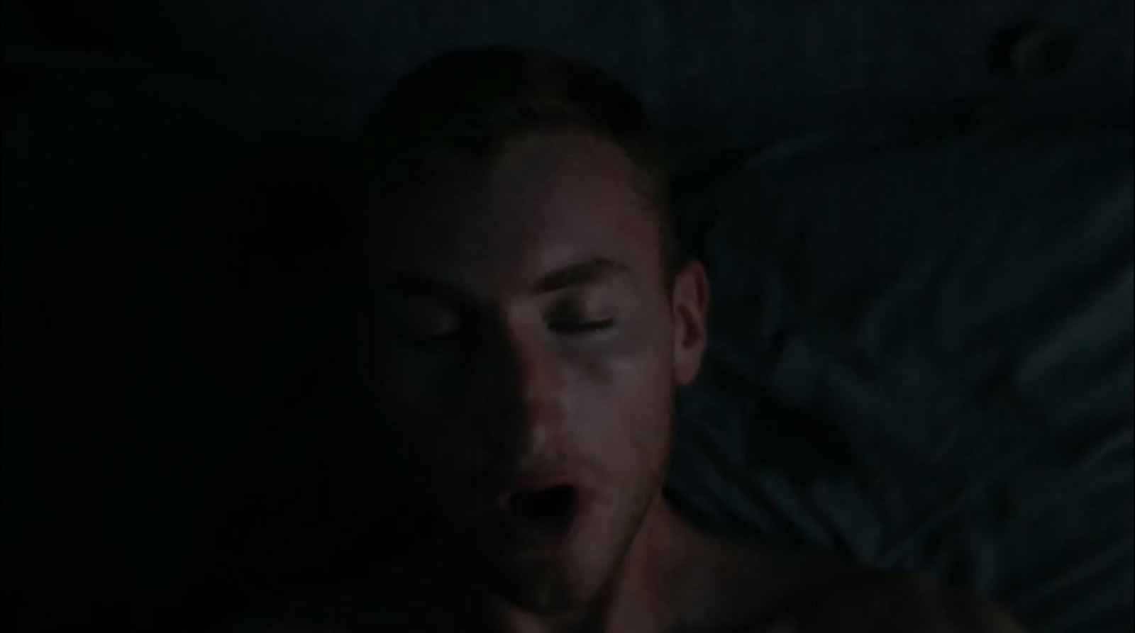 a man laying in bed with his eyes closed