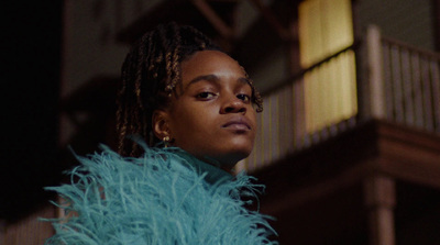 a woman with dreadlocks standing in front of a building