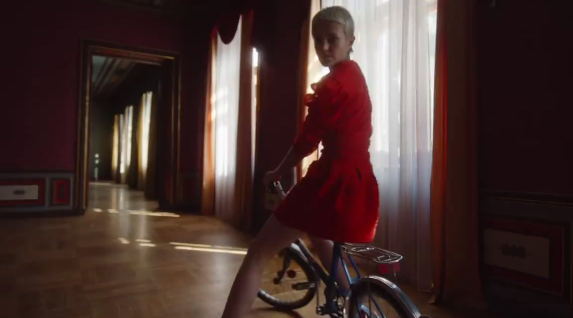 a woman in a red dress riding a bike