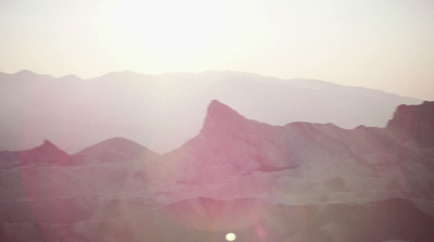 a view of a mountain range with the sun setting