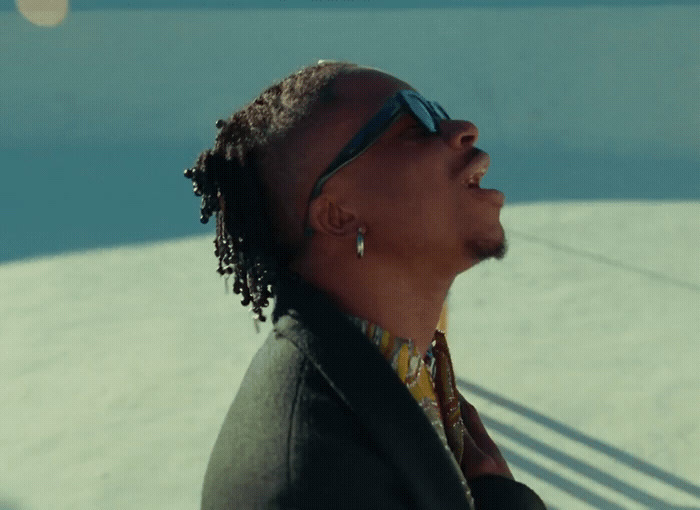 a man with dreadlocks standing in front of a pool