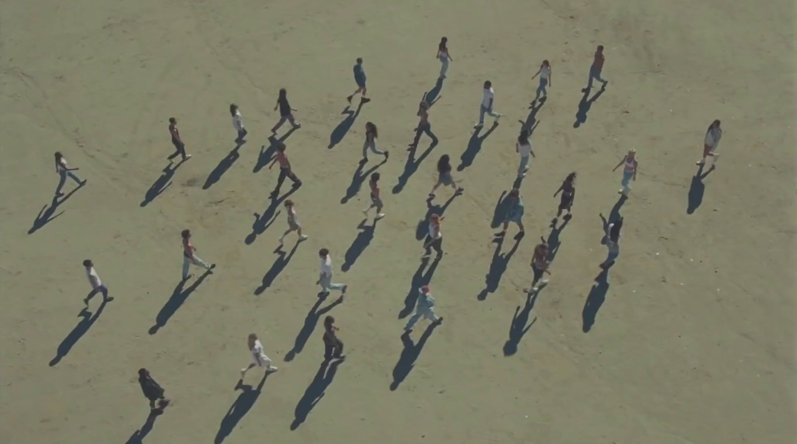 a group of people walking across a sandy beach