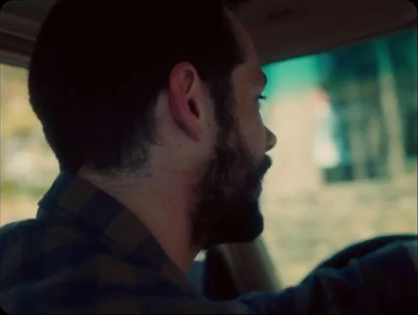 a man with a beard driving a car