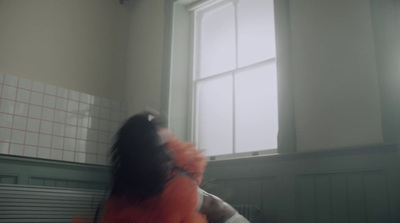 a woman in an orange dress standing in front of a window