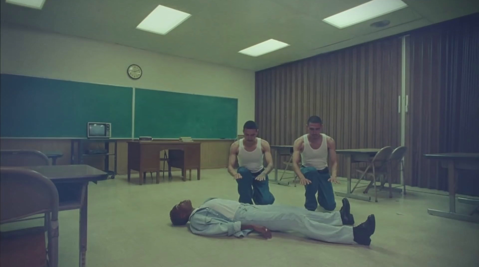 a group of men standing around a man laying on the floor