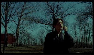 a man talking on a cell phone in a wooded area