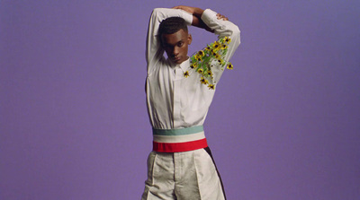 a man in a white suit with flowers on his head