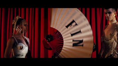 a couple of women standing next to each other in front of a red curtain