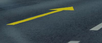 a yellow arrow painted on the road pointing to the right