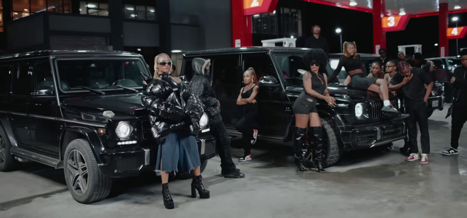 a group of women standing next to a black car