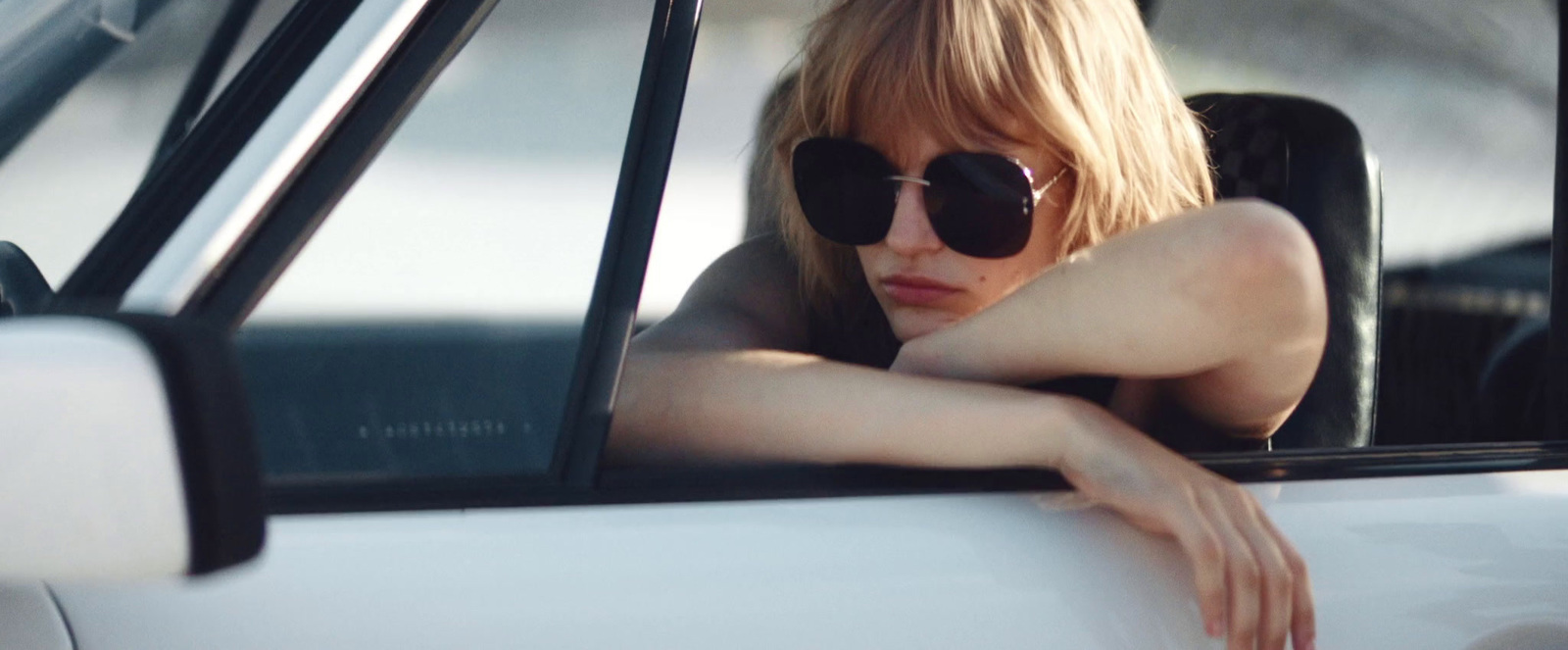 a woman in sunglasses leaning out the window of a car