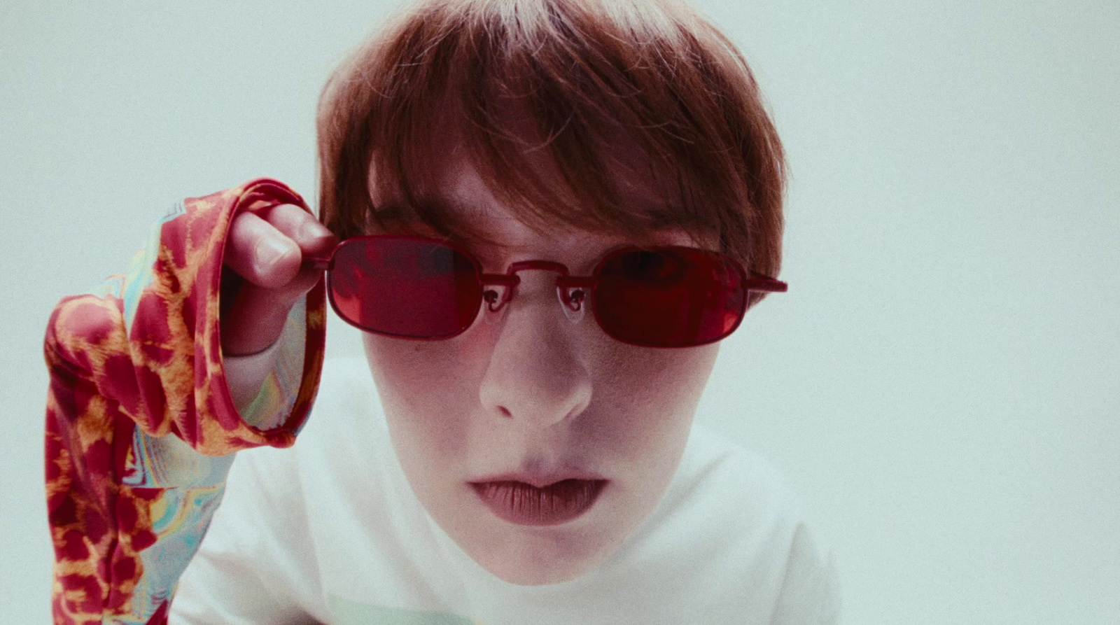 a young boy wearing red sunglasses and a white shirt