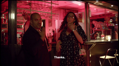 a man and woman standing in front of a bar