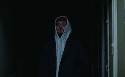 a man in a hoodie standing in a doorway