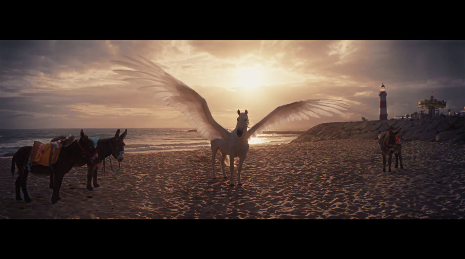 a group of horses standing on top of a sandy beach