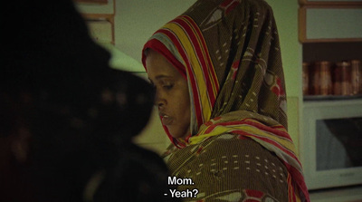 a woman in a colorful scarf standing in a kitchen