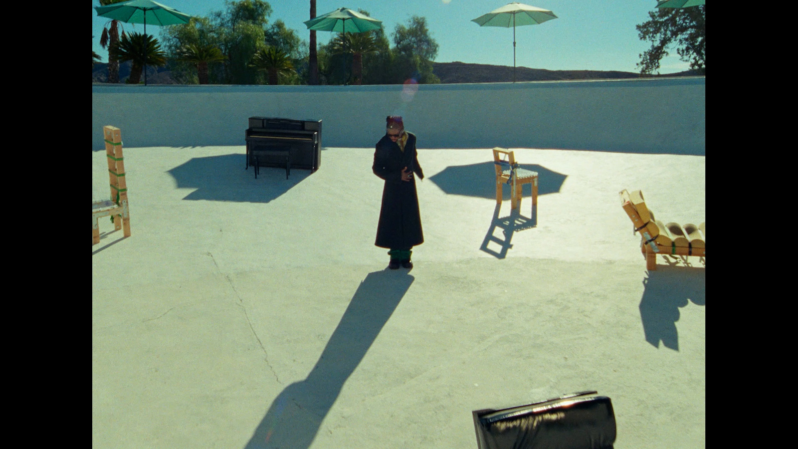 a person standing in a courtyard with chairs and umbrellas