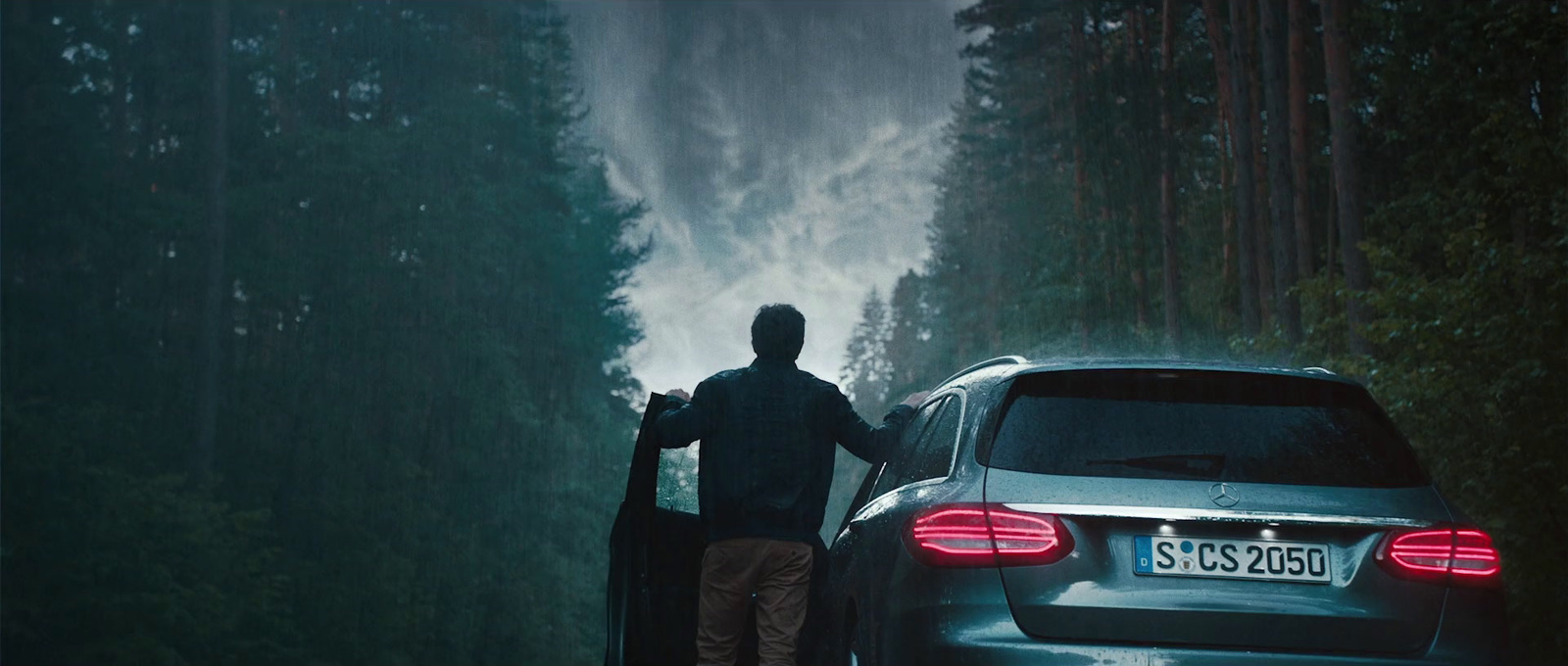 a man standing next to a car on a road