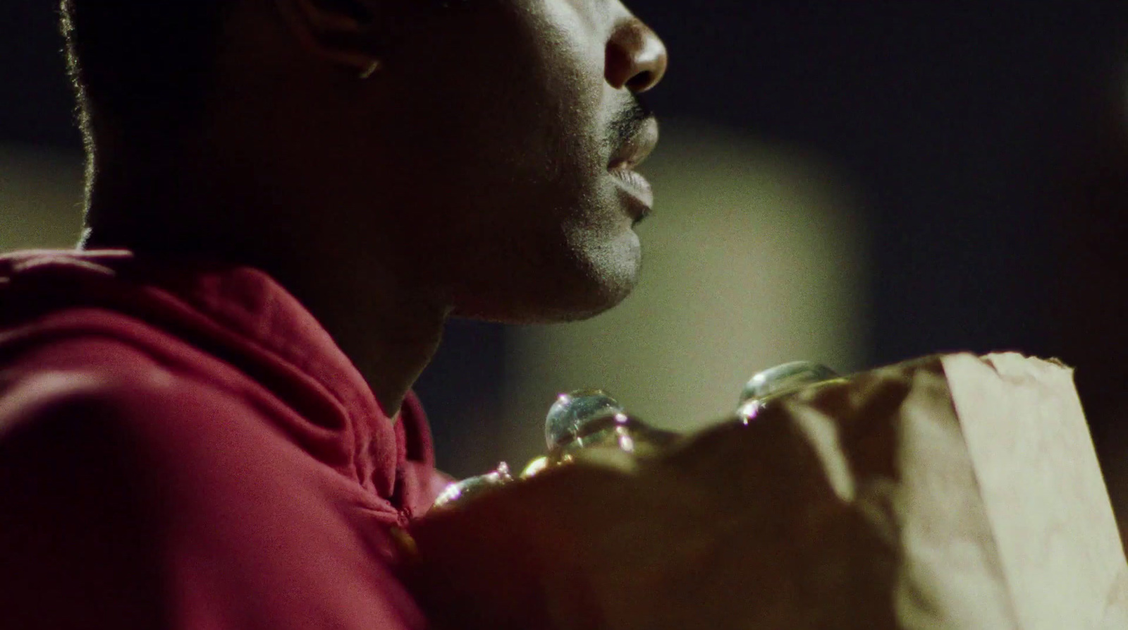 a man in a red sweatshirt holding a brown paper bag