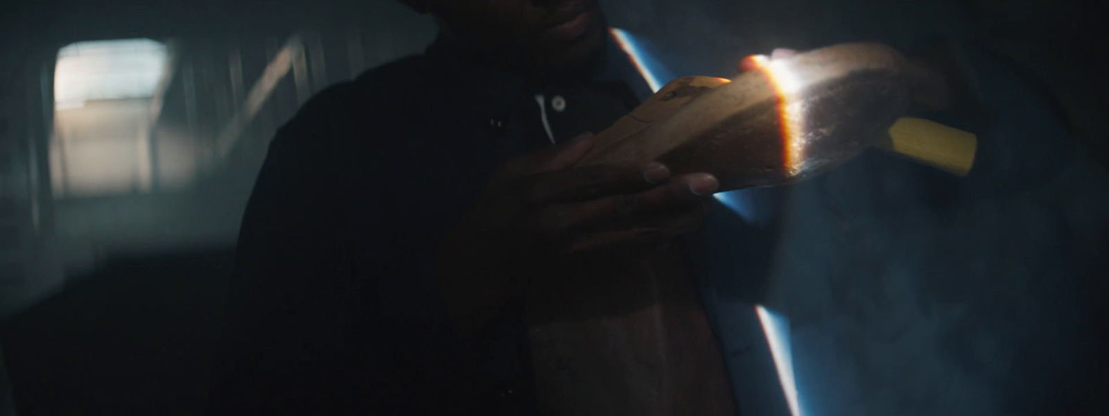 a man holding a wooden object in a dark room