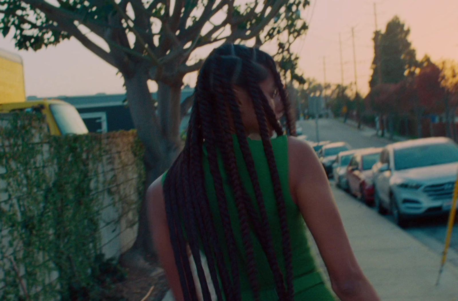 a woman with long braids walking down a sidewalk