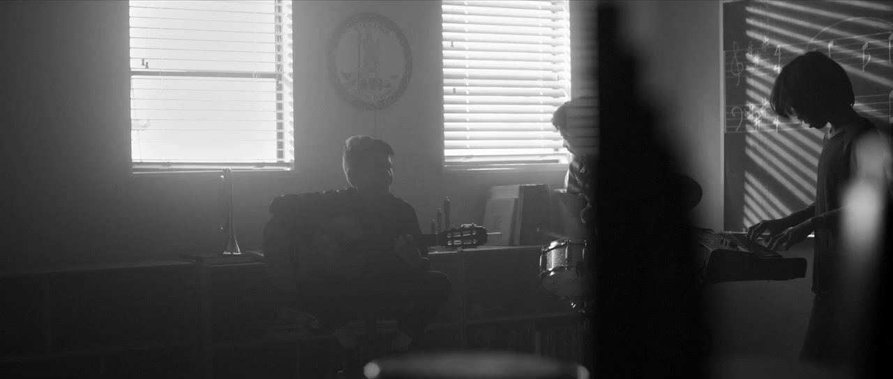 two people standing in a dark room with a clock on the wall