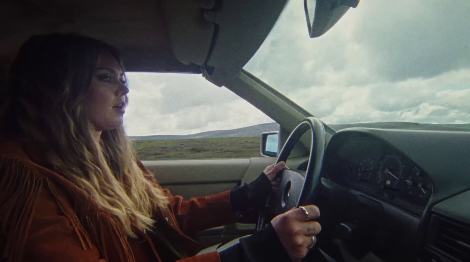 a woman driving a car on a cloudy day