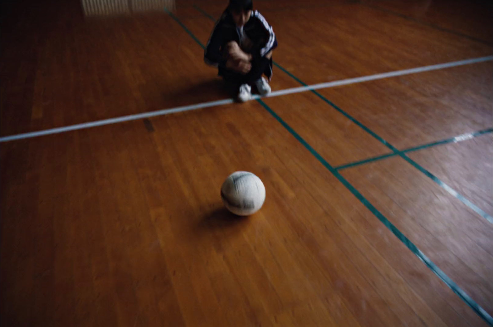 a person kneeling down next to a white ball on a hard wood floor