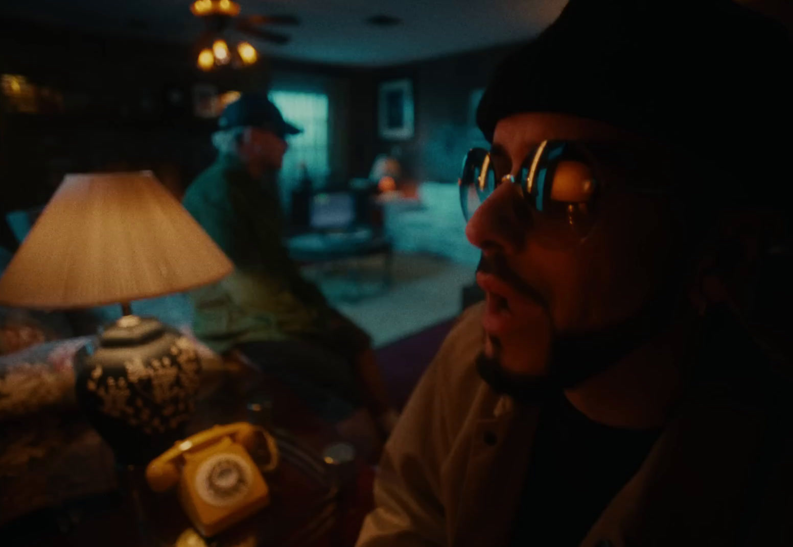 a man in a hat and glasses sitting in a living room