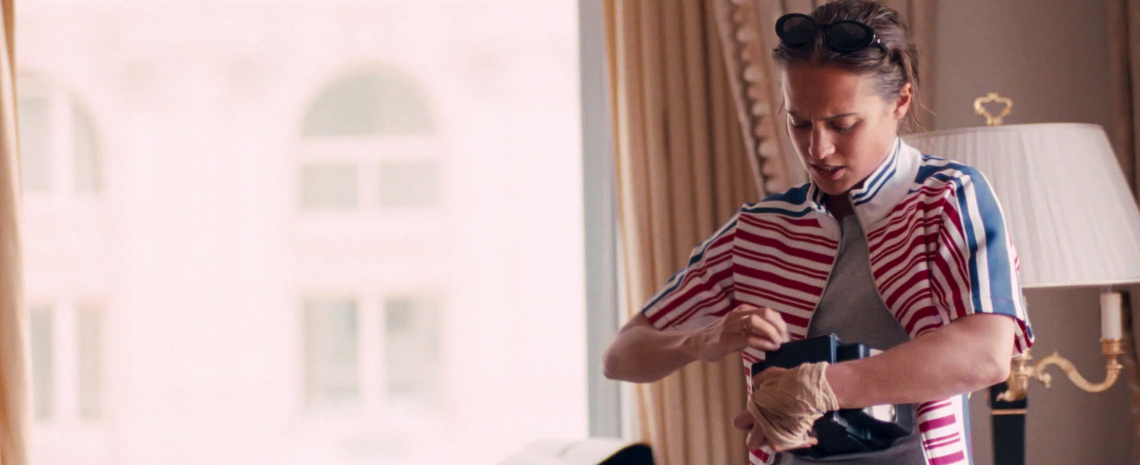 a woman tying a tie in a hotel room