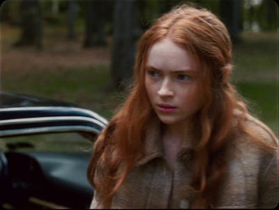 a woman with red hair standing next to a car