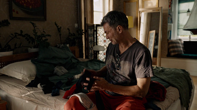 a man sitting on a bed looking at his cell phone