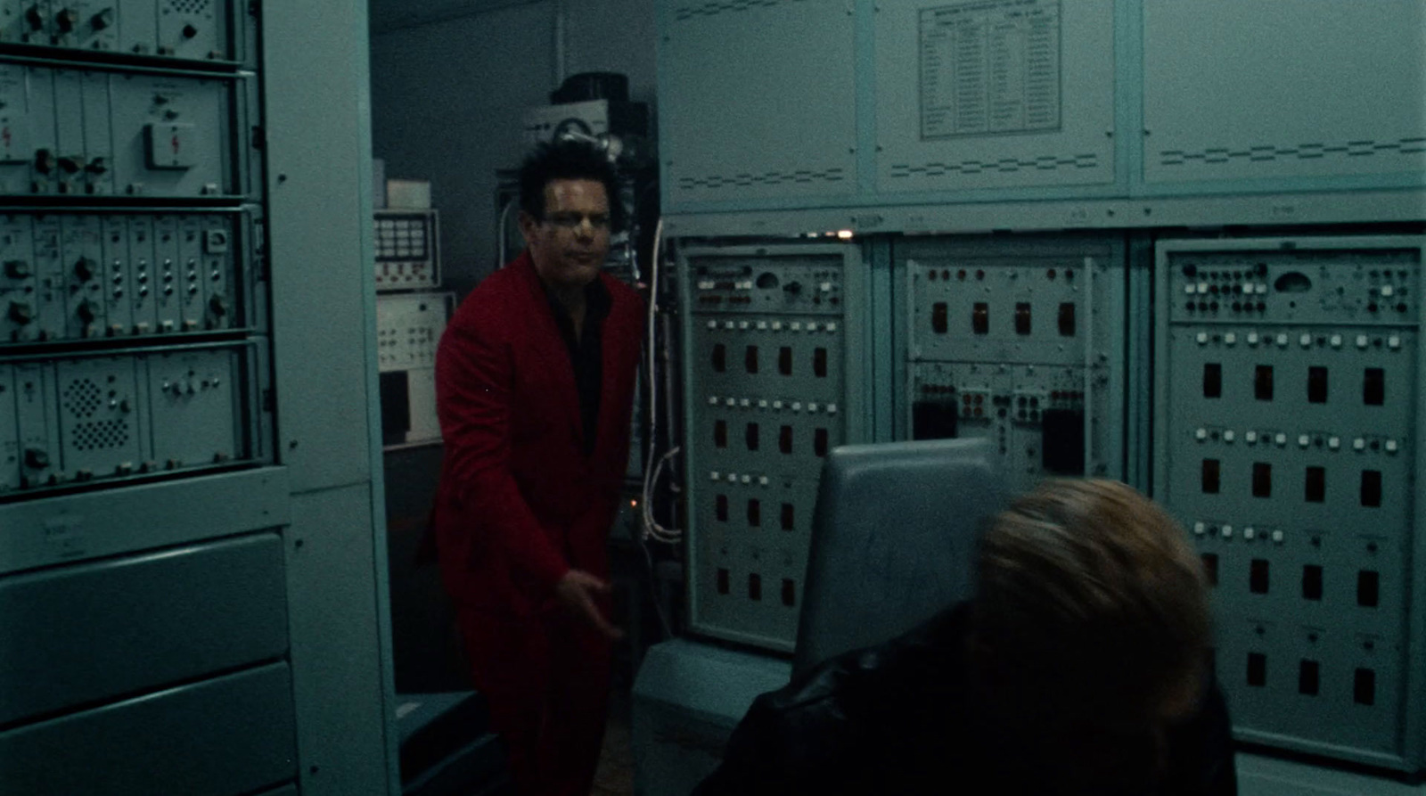 a man in a red suit standing in front of a machine