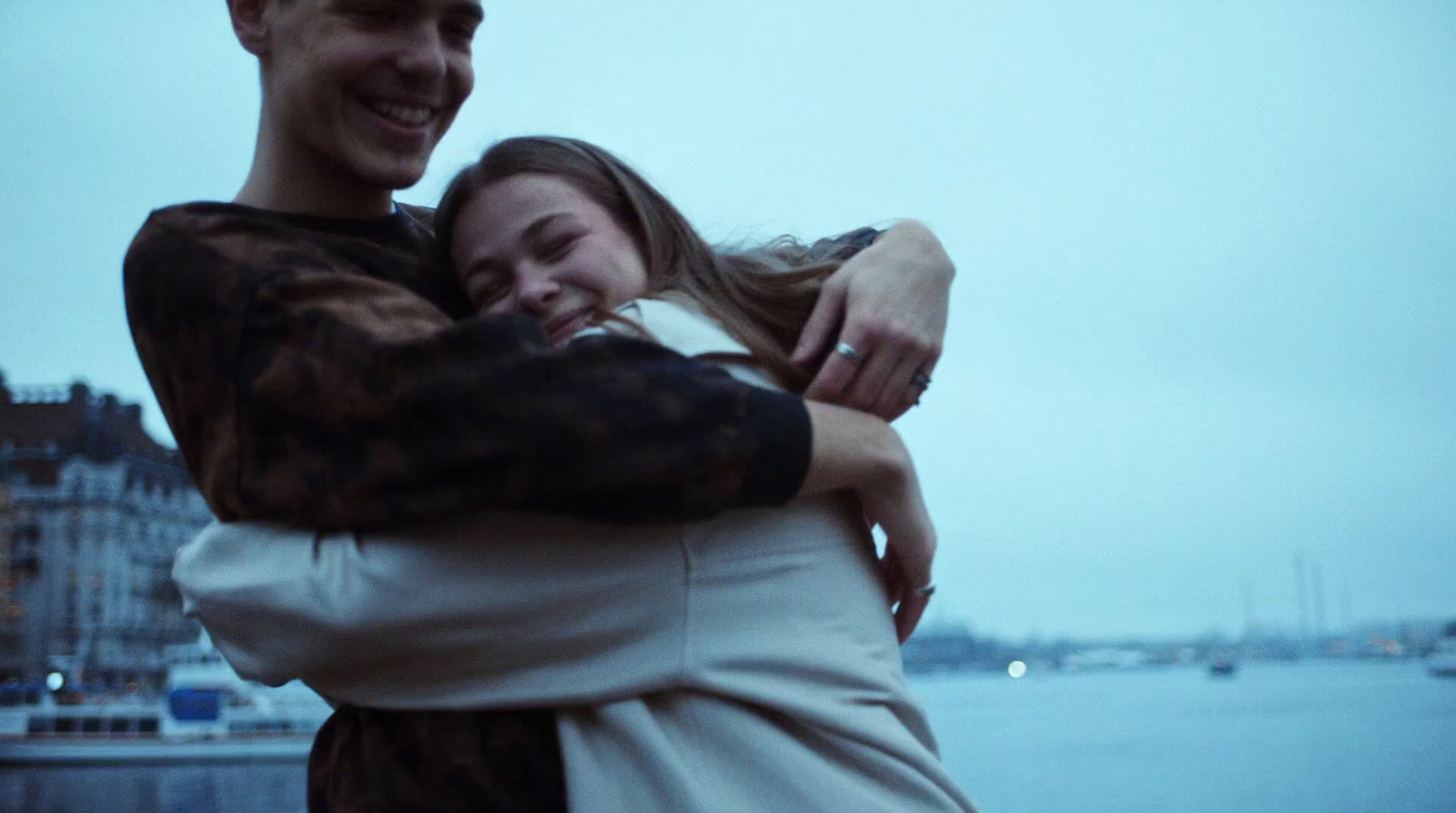 a man and a woman hugging each other by the water