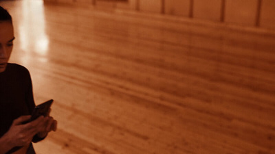 a woman standing on a wooden floor looking at her cell phone