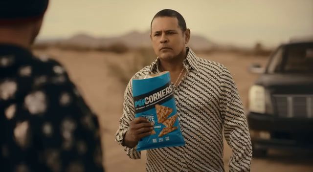 a man holding a bag of cheetos standing next to a truck